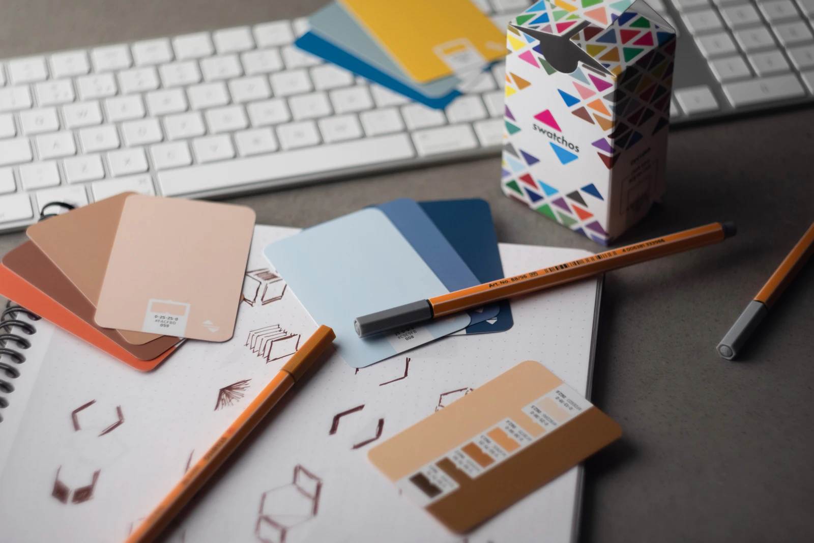 Mesa de trabajo con bocetos de logo y muestras de colores